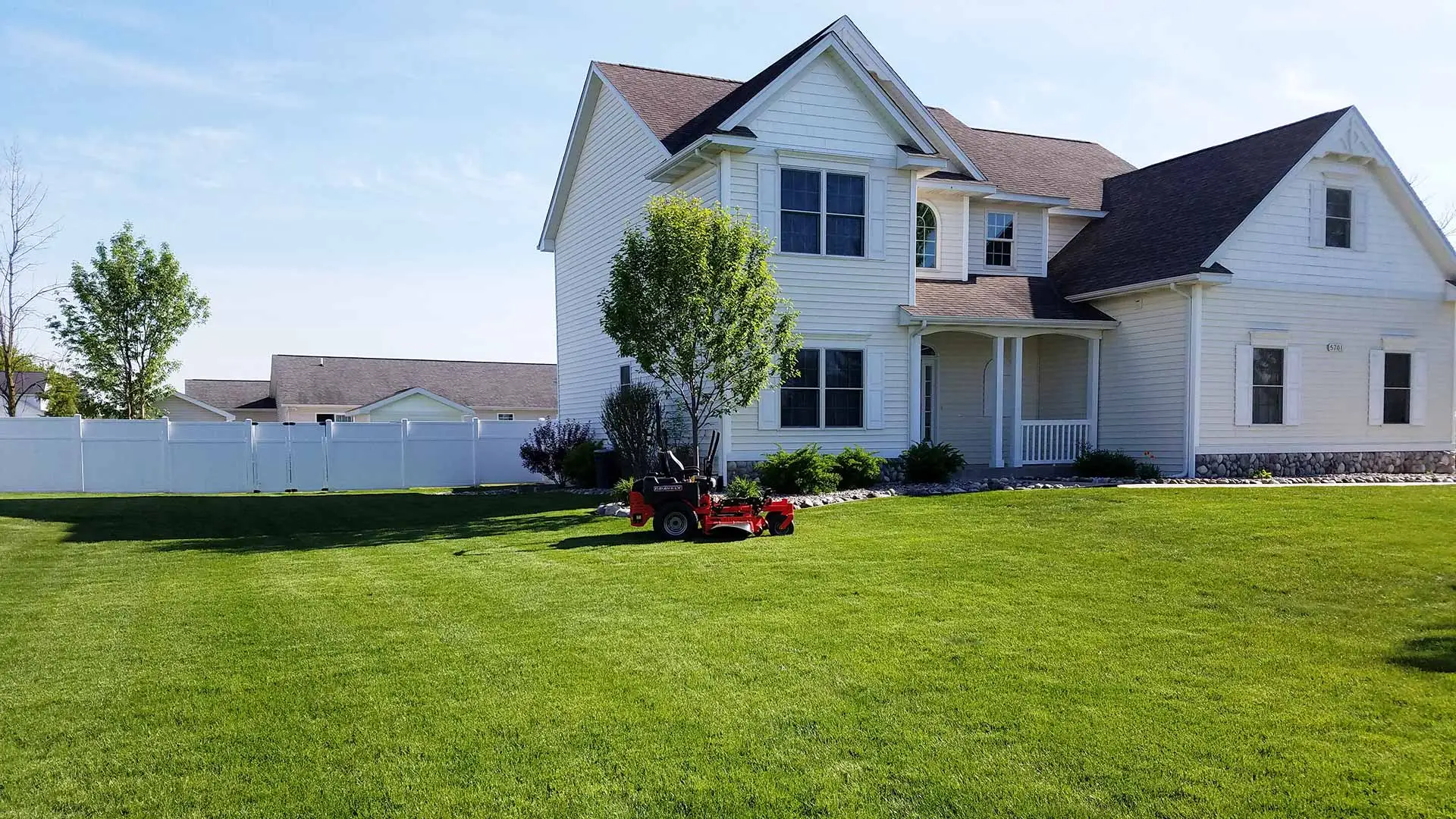Large, freshly mowed front yard with a parked riding mower.