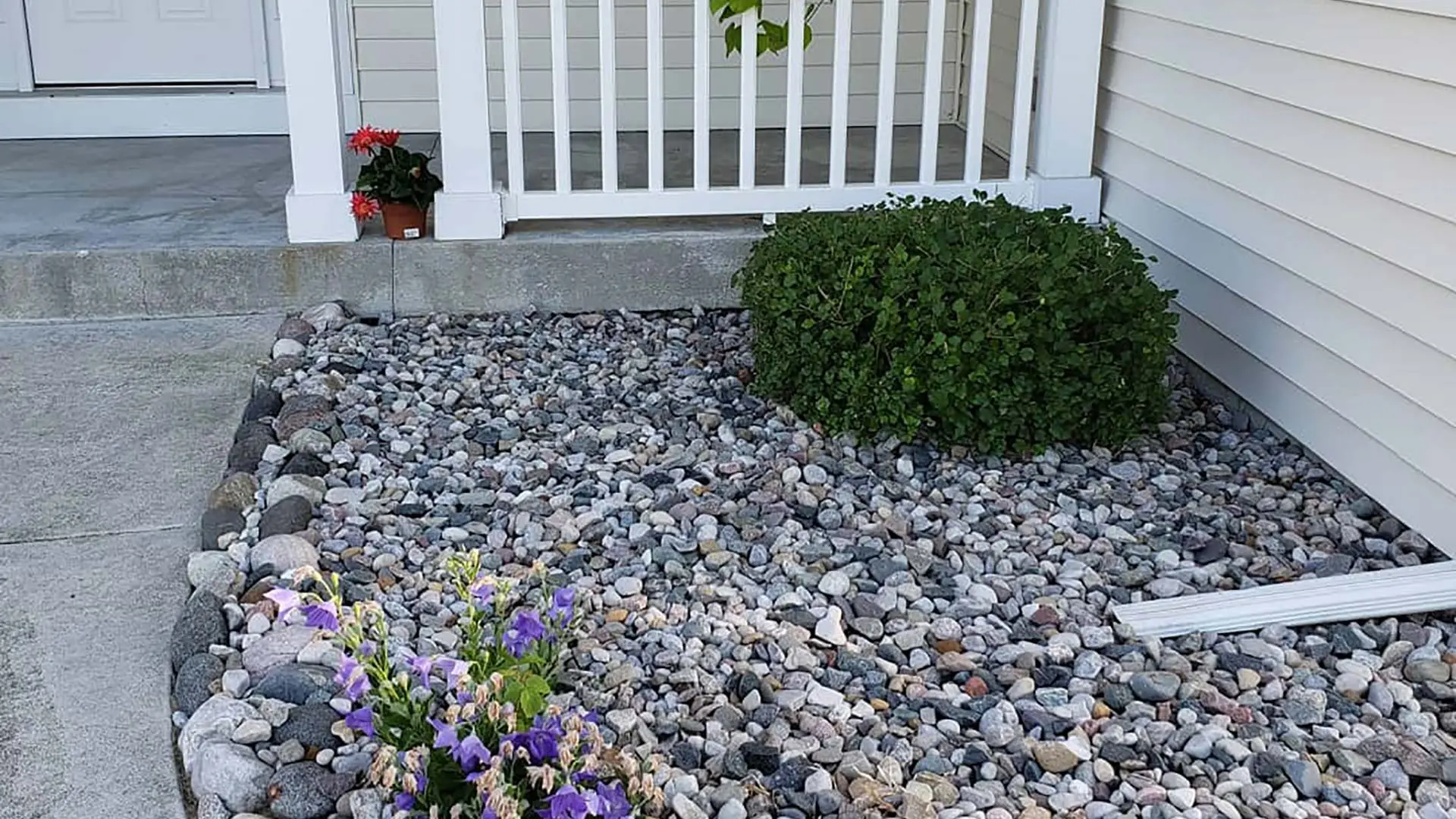 Decorative river rock has been installed in this landscape bed in Saginaw, MI.