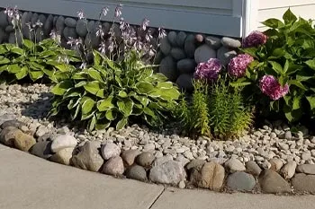 Landscaping bed with river rock and maintained landscaping at a home in Saginaw, MI.